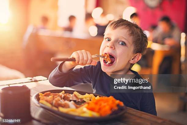 little boy enjoying dinner at the restaurant - children restaurant stock pictures, royalty-free photos & images