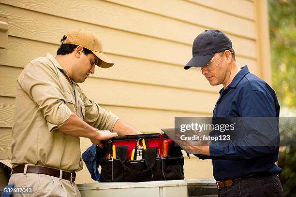 air conditioner repairmen work on home unit. blue collar workers. - hvac service stock pictures, royalty-free photos & images