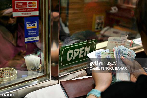 Customer counts ringgit bills at the service window of a money changer in Kuala Lumpur, 22 July 2005. The Malaysian ringgit was appreciating...