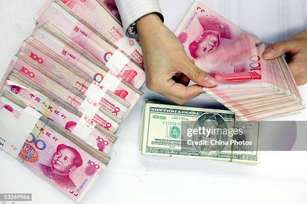 Clerk counts stacks of Chinese yuan and U.S. Dollars at a bank on July 22, 2005 in Shanghai, China. The People's Bank of China, the central bank,...