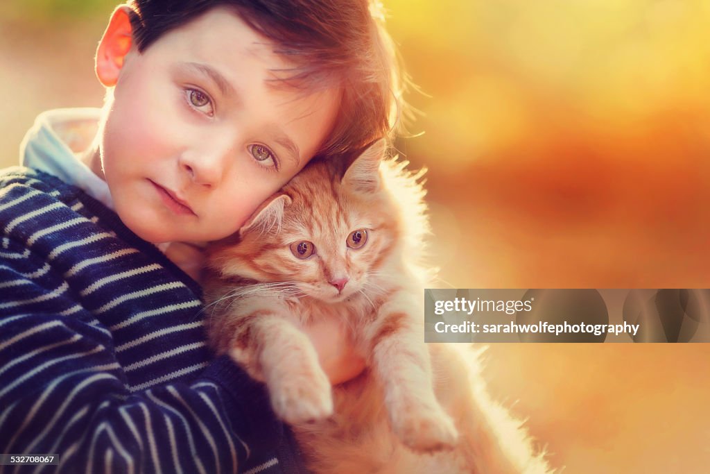 Young boy hugging orange cat