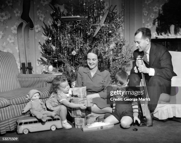 family sitting in front of christmas tree - christmas tree 50's stockfoto's en -beelden