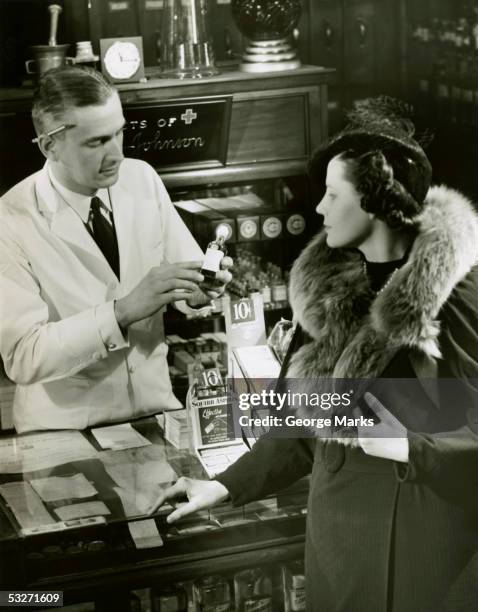 pharmacist fills prescription for woman - 20th century stockfoto's en -beelden