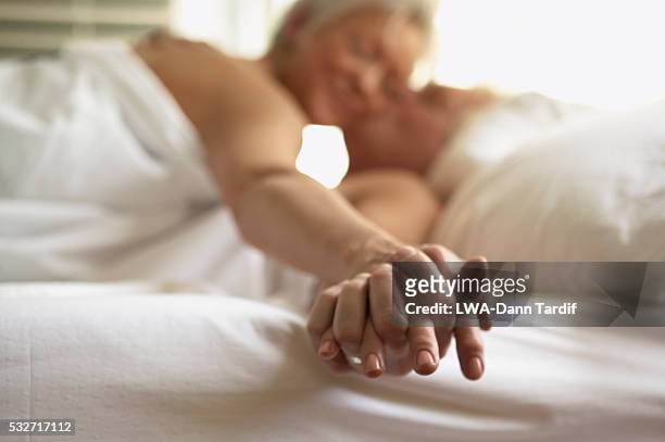 senior couple holding hands in bed - 性的行動 ストックフォトと画像