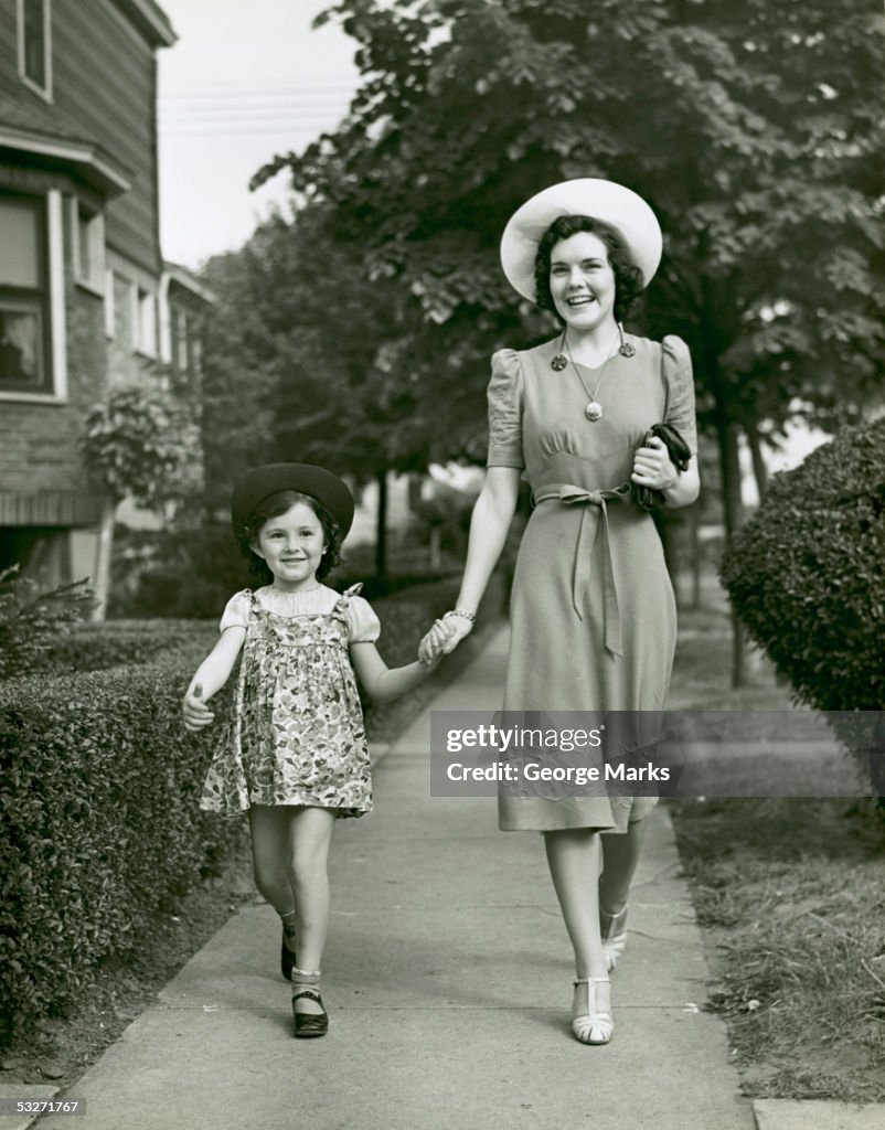 Mother and little daughter walking in suburbs