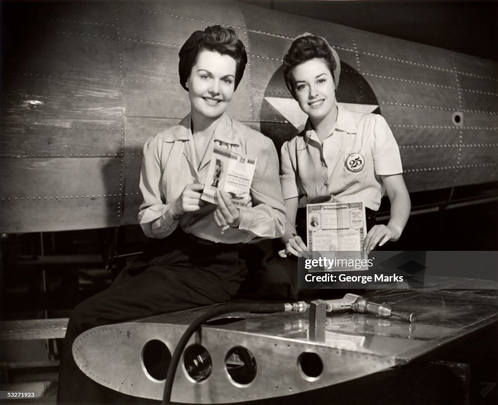 WW II aircraft workers holding savings bonds