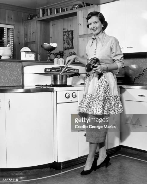 apron housewife at kitchen stove - retro wife stock pictures, royalty-free photos & images