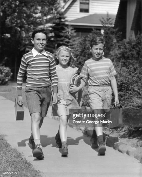 two boys and one girl walking with books - 1950s school stock pictures, royalty-free photos & images