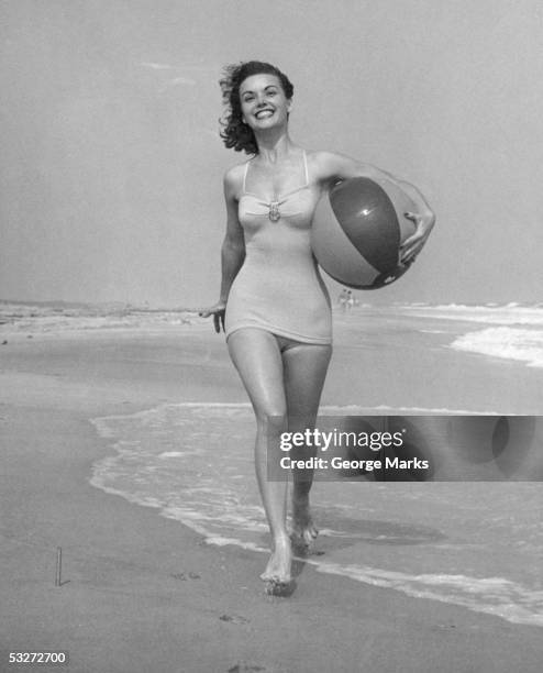 woman walking on beach with beach ball - retro swimwear stock pictures, royalty-free photos & images