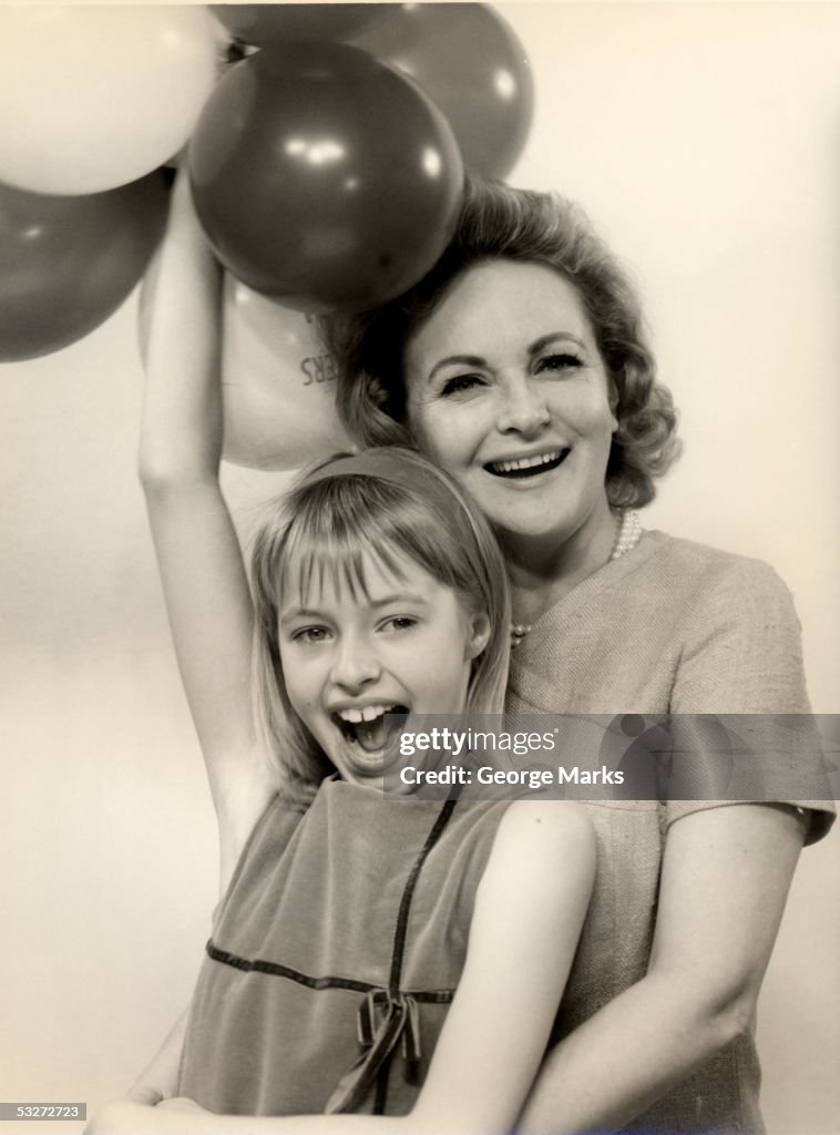 Smiling mother and daughter with balloons