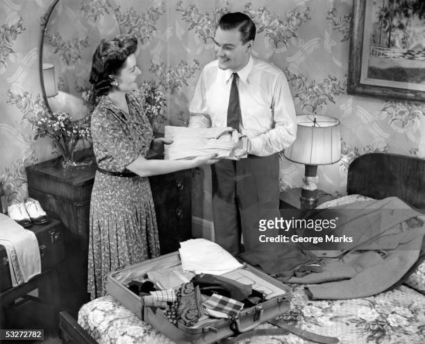 woman helping husband pack suitcase - 1950s bedroom stock pictures, royalty-free photos & images