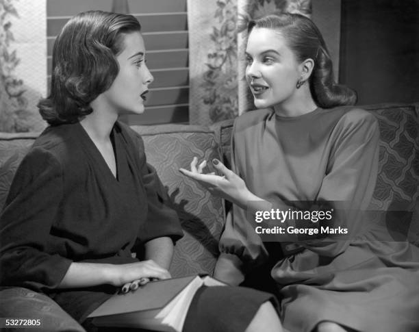 two woman sitting on couch talking - woman 1950 stock-fotos und bilder