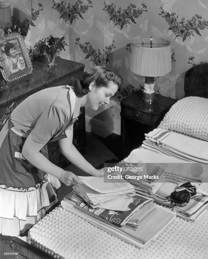 Housewife sorting ironed linens & towels