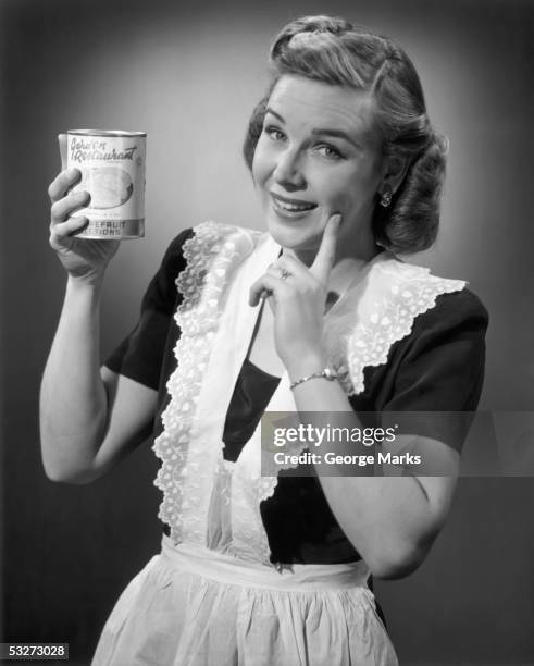 housewife in apron holding a can of fruit - 1950s housewife stockfoto's en -beelden