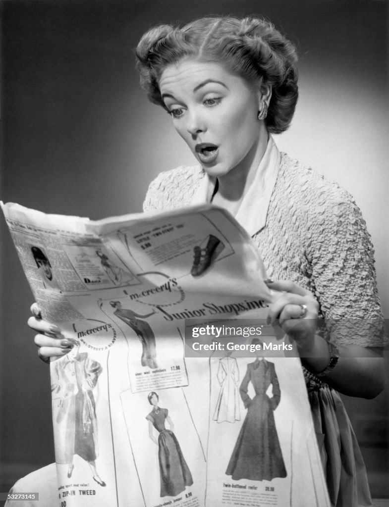 Woman reading newspaper with look of surprise