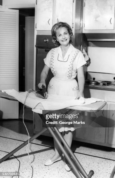 smiling housewife ironing - stereotypical housewife stock-fotos und bilder
