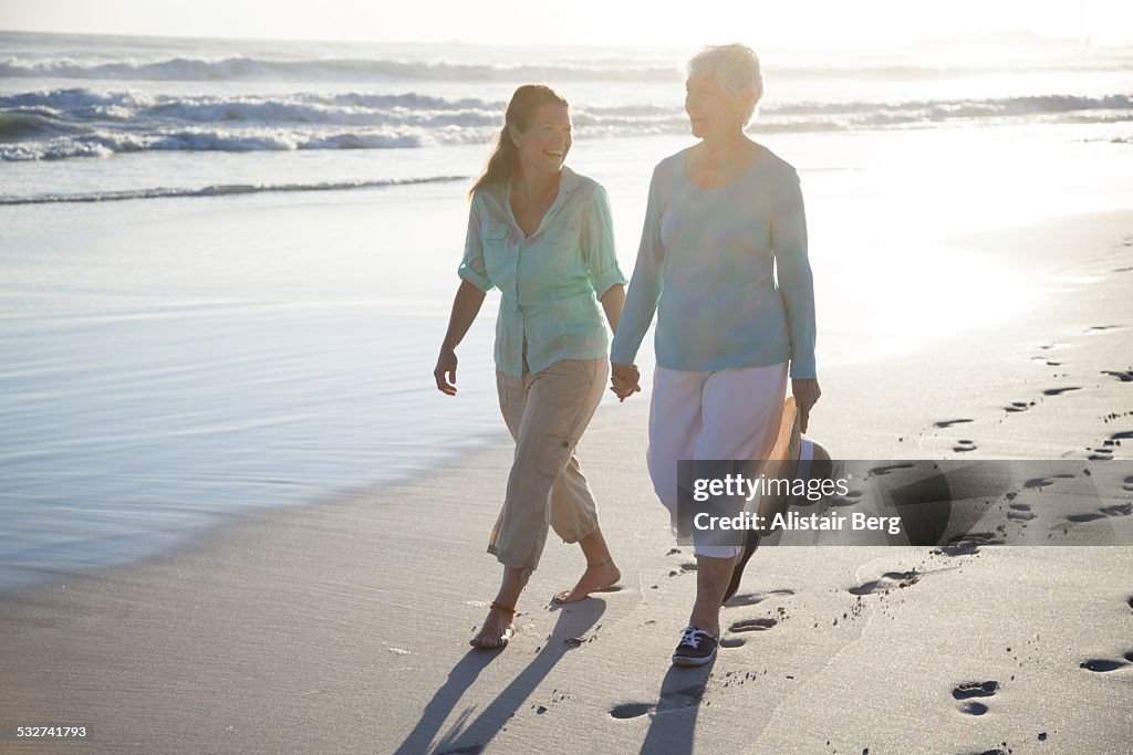 Senior mother and daughter walking on beach