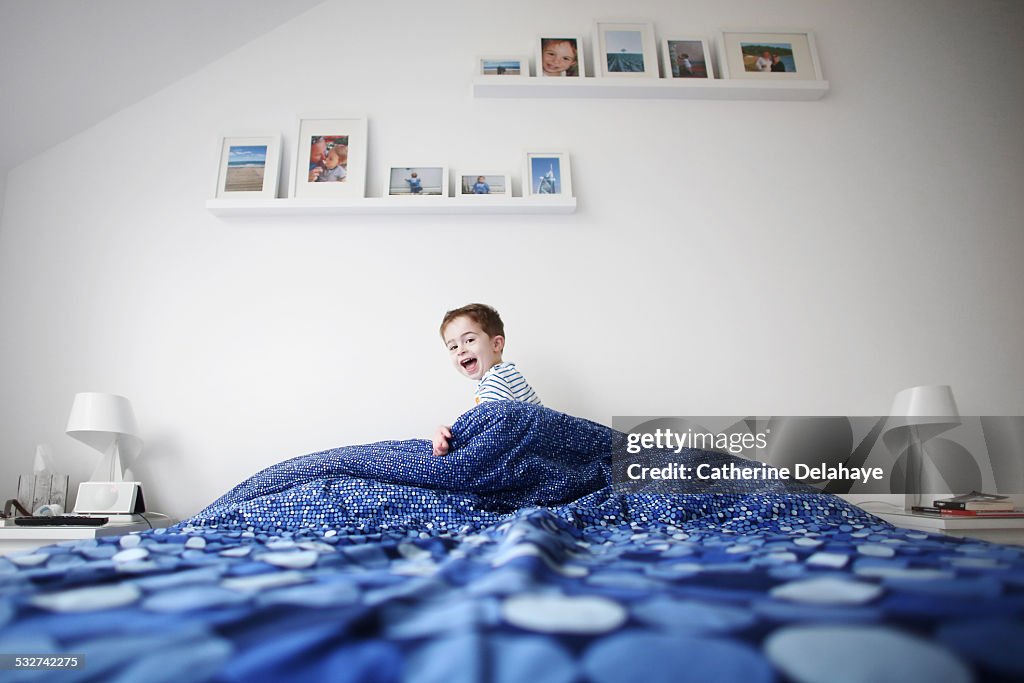 A 3 years old boy playing in his parents bedroom