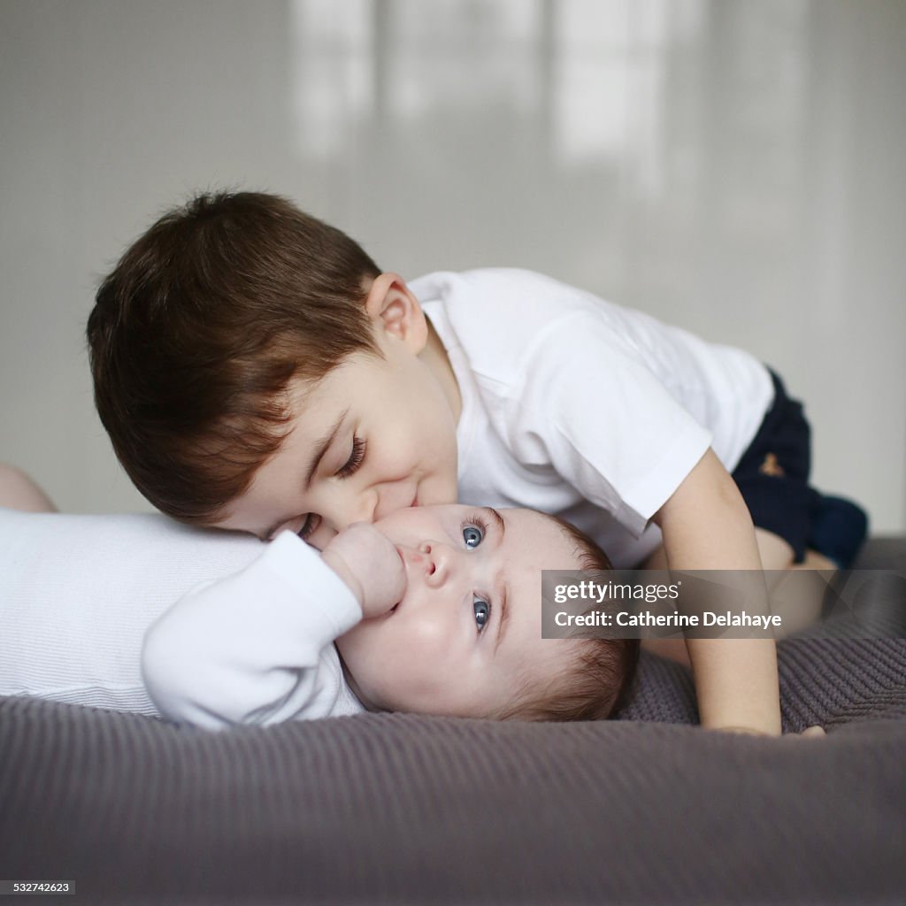 A 3 years old boy kissing his baby brother