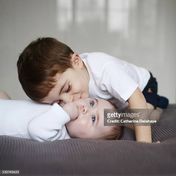 a 3 years old boy kissing his baby brother - 2 3 years stock pictures, royalty-free photos & images