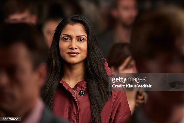 portrait of woman standing in crowd & smiling - buitenbeentje stockfoto's en -beelden
