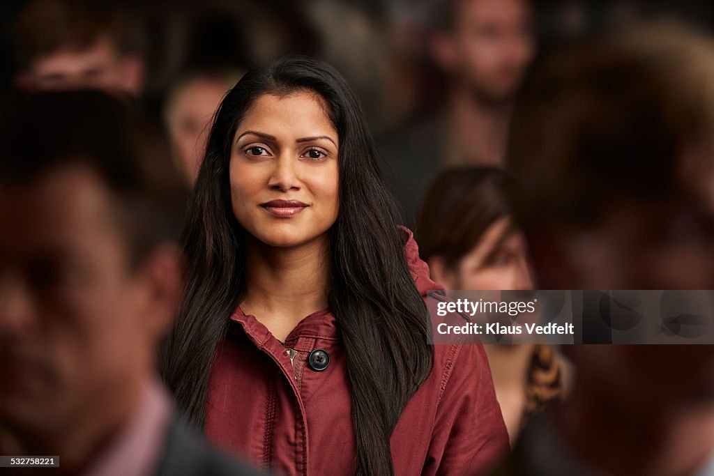 Portrait of woman standing in crowd & smiling