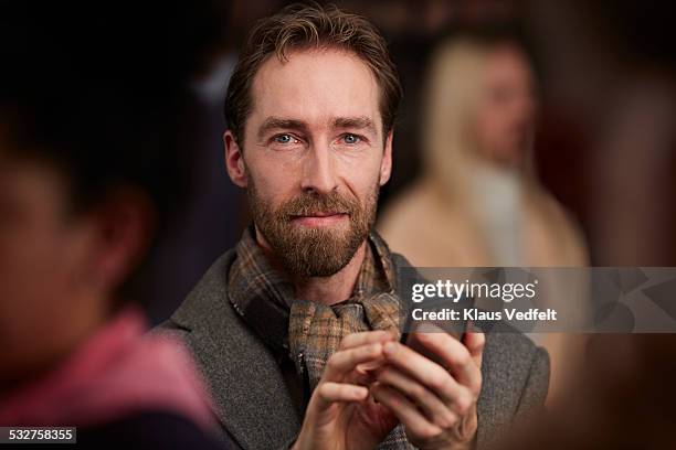 portrait of man holding phone, standing in crowd - one person in crowd stock pictures, royalty-free photos & images