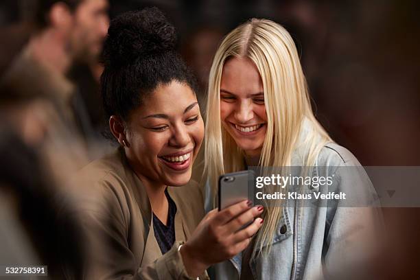 two girlfriends looking at smartphone together - man showing phone stock pictures, royalty-free photos & images