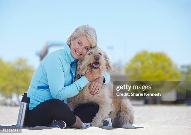 middle-aged woman hugging her labradoodle - labradoodle stock pictures, royalty-free photos & images
