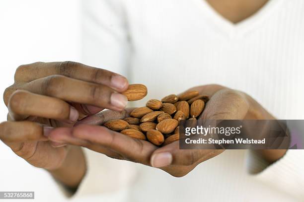 woman eating almonds - eating nuts stock-fotos und bilder