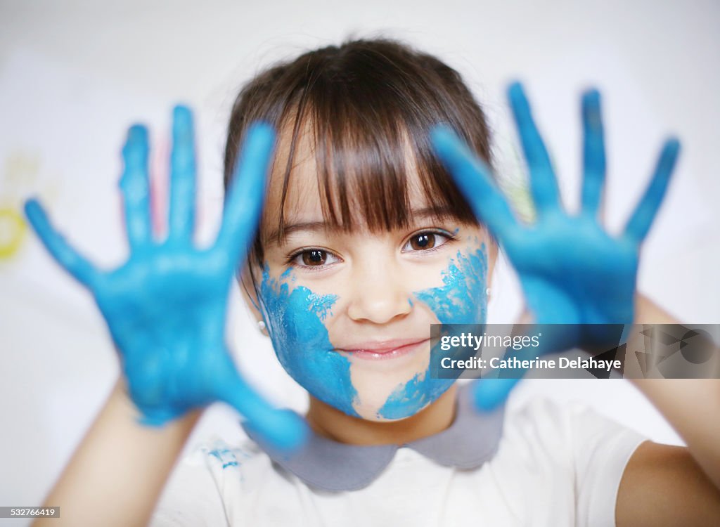 A 4 years old girl with paint on her hands