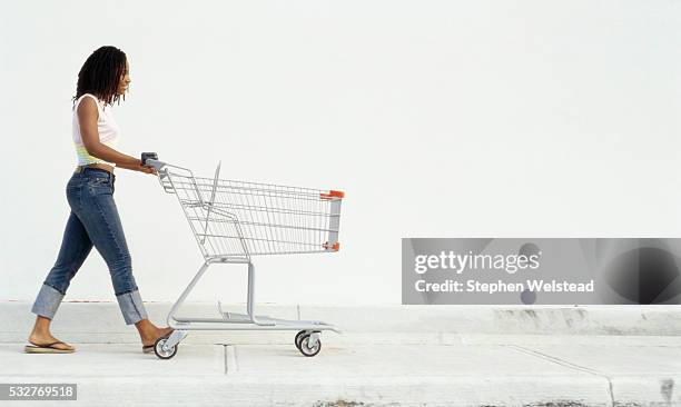 shopper pushing cart - grocery cart fotografías e imágenes de stock