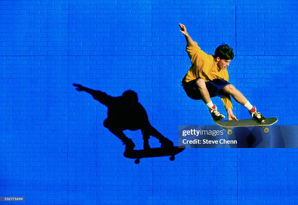 Skateboarder Flying Past Blue Brick Wall