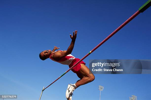 high jumper doing fosbury flop - hochsprung stock-fotos und bilder