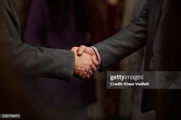 close-up of 2 men making handshake in crowd - business man in crowd stock pictures, royalty-free photos & images