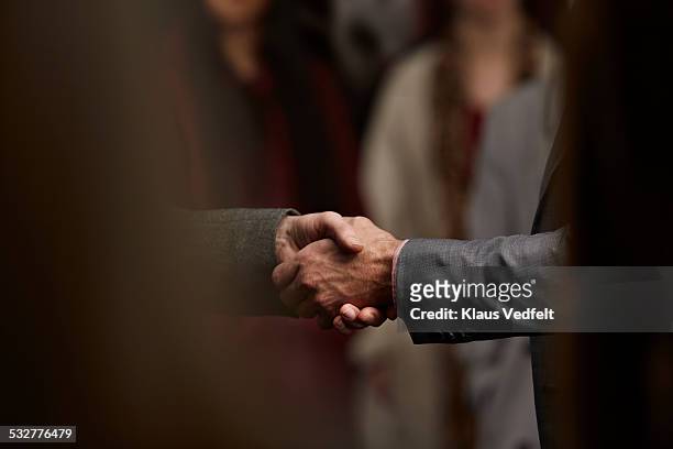 close-up of 2 men making handshake in crowd - trust foto e immagini stock