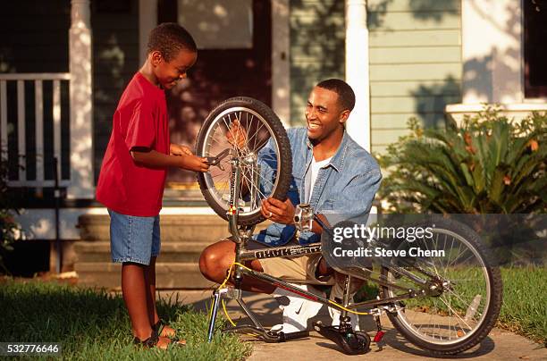 father and son fixing a bicycle - black man bike repair stock pictures, royalty-free photos & images