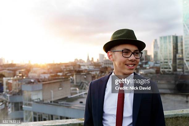 teenage boy dressed in a cool suit and hat standing on a rooftop looking over the city - hat and suit stock pictures, royalty-free photos & images