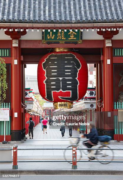 woman cycling past kaminari-mon, senso-ji temple - asakusa senso temple stock pictures, royalty-free photos & images