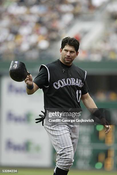 First baseman Todd Helton of the Colorado Rockies tosses his hemet to the bat boy after making an out to end an inning during a game against the...