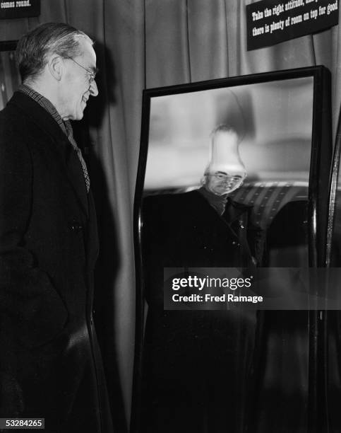 Labour Chancellor of the Exchequer Sir Stafford Cripps views his reflection in a distorting mirror at a C.O.I. Exhibition in London entitled 'On Our...