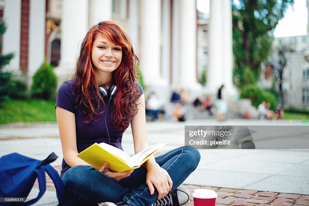 Student girl reading book in front of Univercity