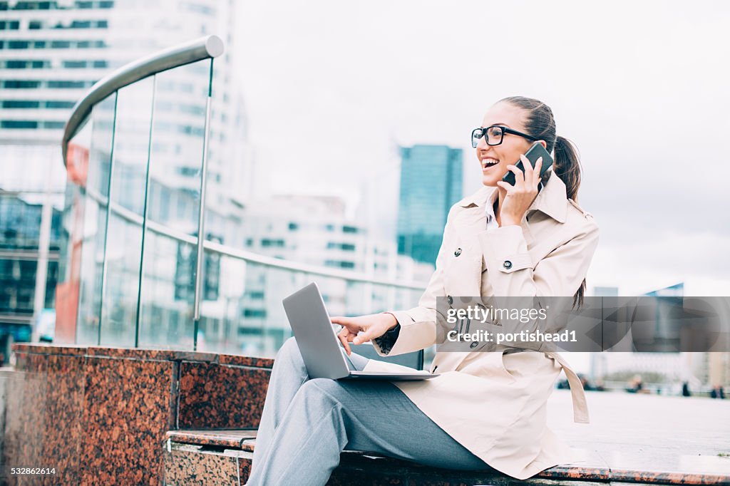 Young bussineswoman using laptop and talking on the phone