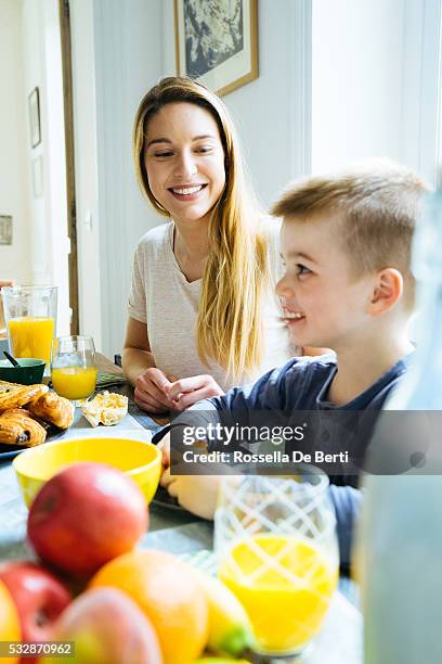 happy family, mother and son, having breakfast together at home - family orange juice stockfoto's en -beelden