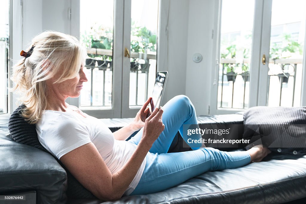 Ältere Erwachsene Frau Lesen der tablet-PC auf der Couch