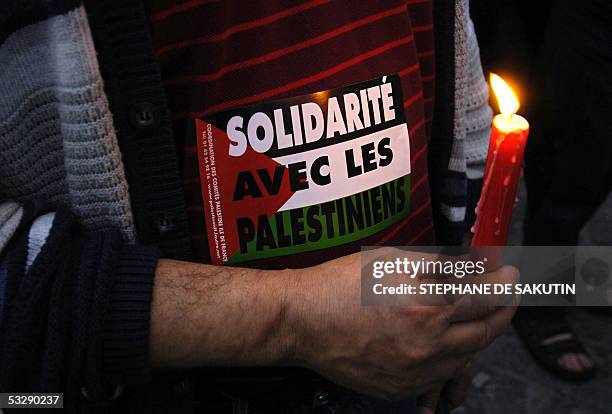 Man holds a candle next to a sticker reading "Solidarity with Palestinians", during a demonstration against the visit of Israeli Prime Minister Ariel...