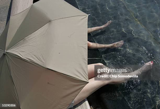 Paige Rose, 12 years-old, and her mother, Cindy Rose, of St. Louis, MO, take shade under an umbrella while they dip their feet in the fountain in the...