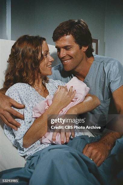 American actors Kim Lankford and James Houghton of the CBS prime time soap opera 'Knot's Landing,' pose with a prop baby as they pretend to be in a...