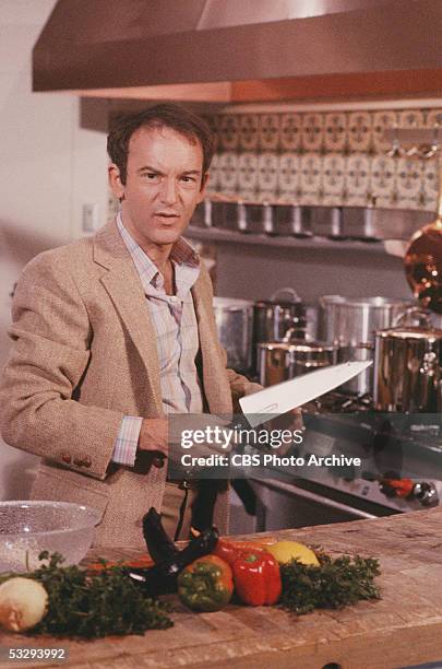 American actor John Pleshette of the CBS prime time soap opera 'Knot's Landing,' stands with a large knife in a fake kitchen in the episode...