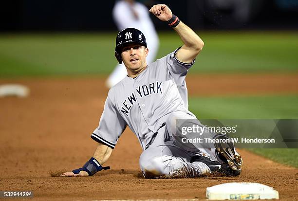 Dustin Ackley of the New York Yankees slides into third base safe against the Oakland Athletics in the top of the six inning at O.co Coliseum on May...